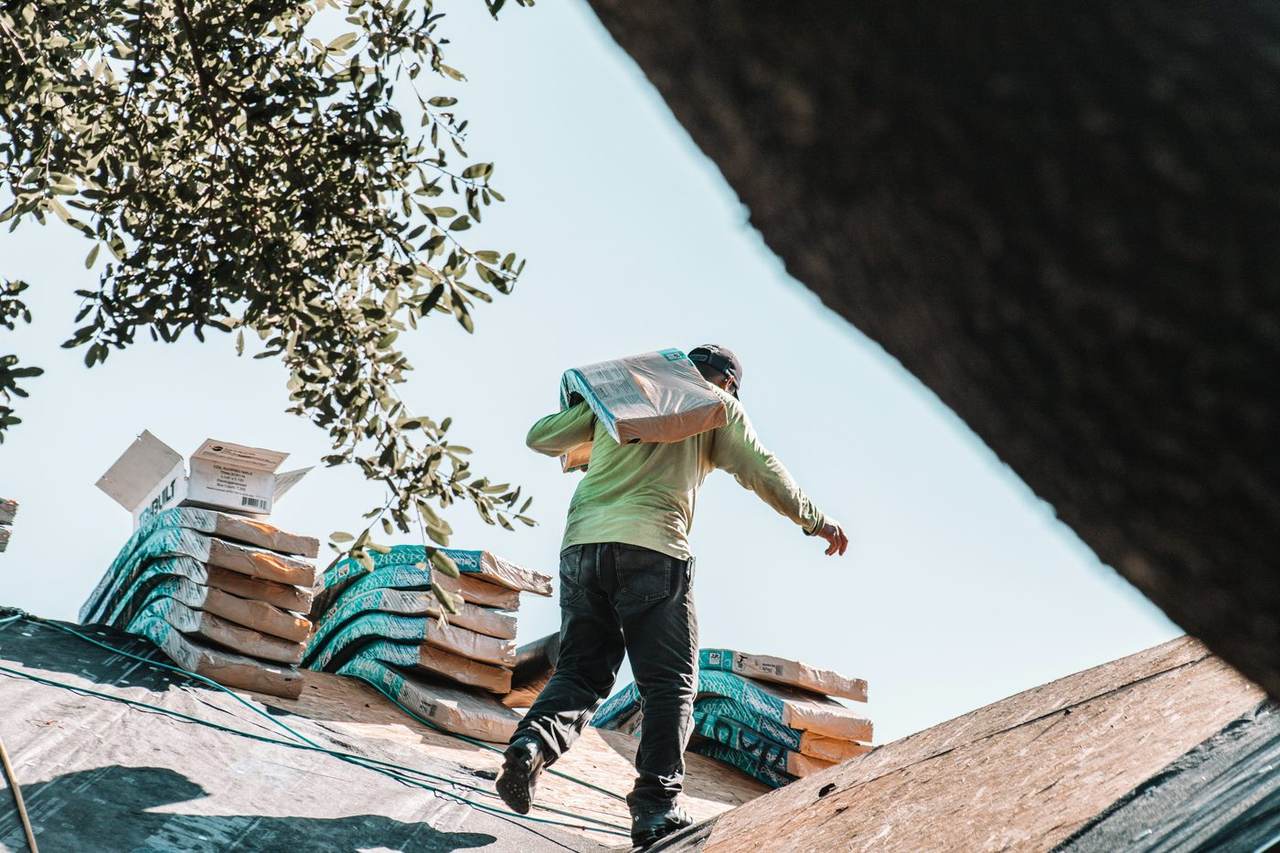 Roofer carrying waterproofing materials onto a roof for a repair